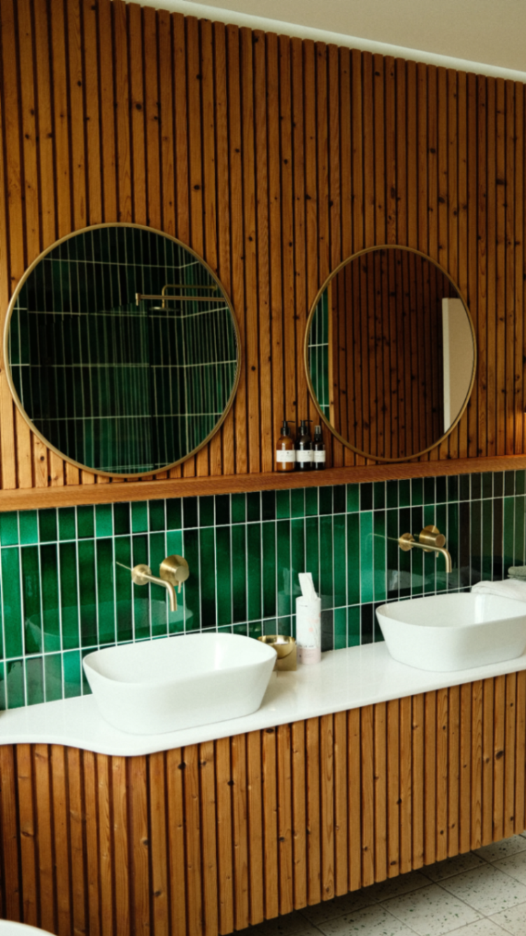 Bathroom with emerald tile, brass and timber