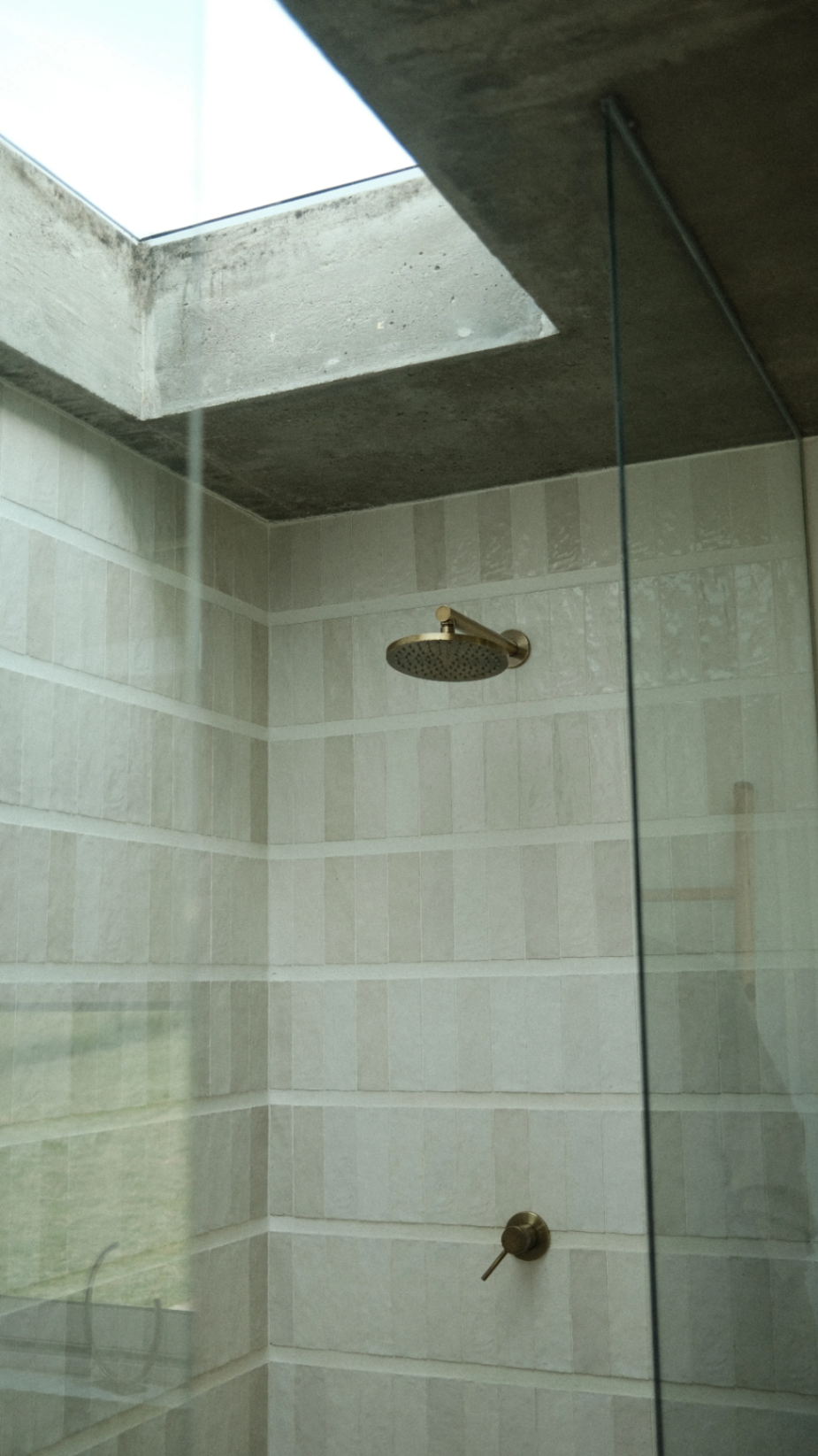 Skylit shower in tonal cream tile and brass